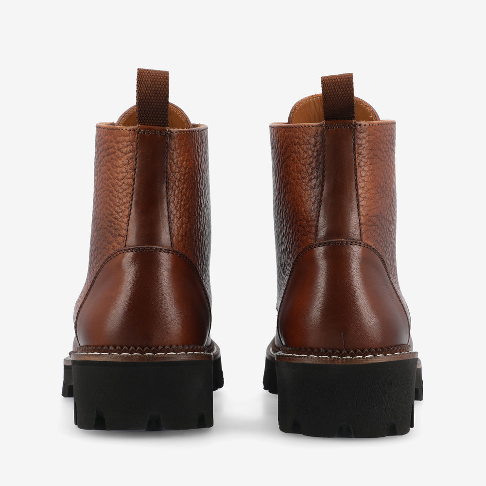 Rear view of a pair of brown leather ankle boots with black chunky soles.