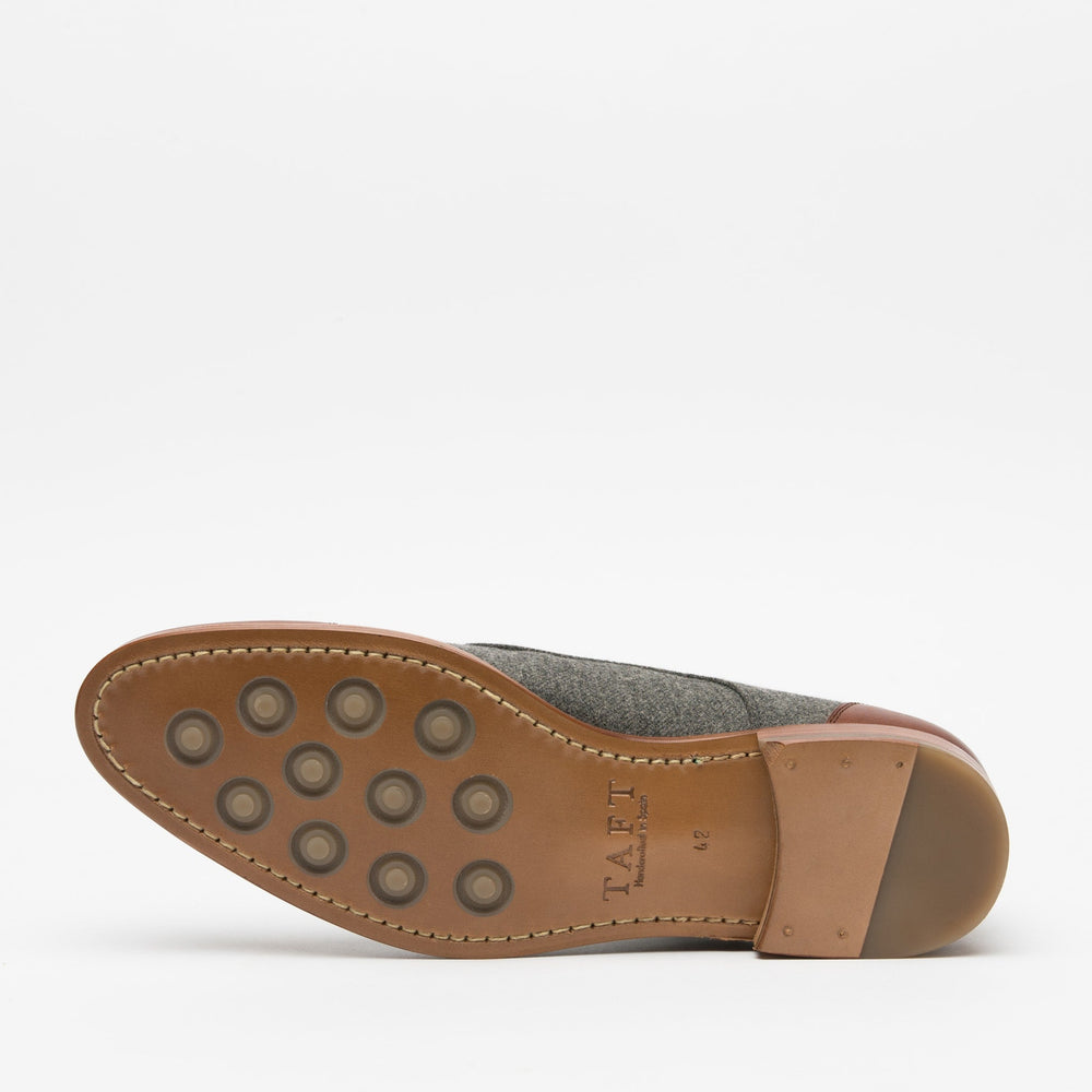 View of the sole of a dress shoe with a leather and rubber bottom, featuring multiple circular rubber grips and a stacked heel.