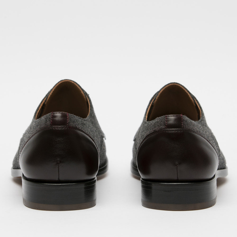 Back view of a pair of dress shoes featuring dark brown leather heels and gray suede uppers.