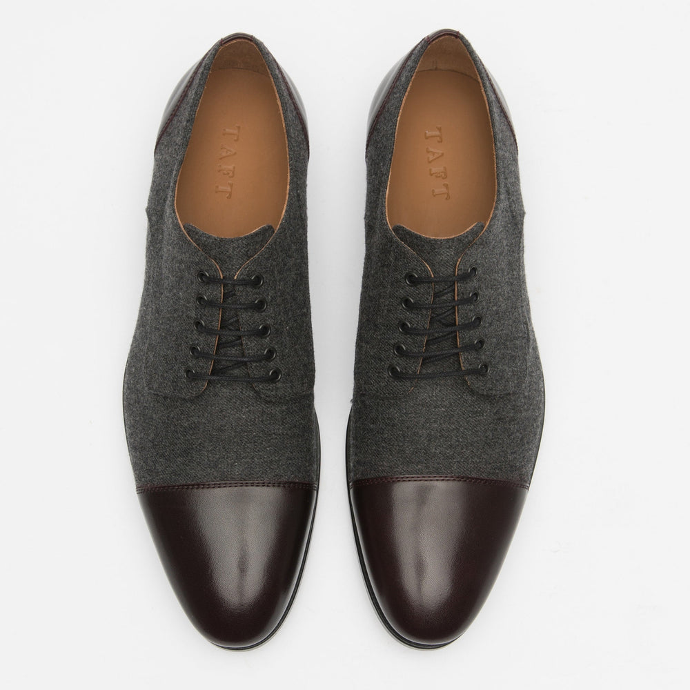 Top-down view of a pair of men's dress shoes. The shoes have grey fabric uppers and dark brown leather toe caps and heels.