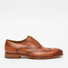 A single brown leather brogue shoe with decorative perforations and dark laces, shown from the side.