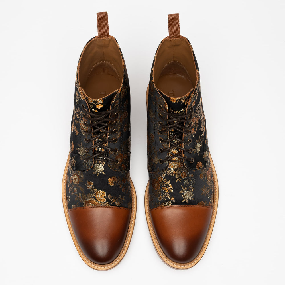 A pair of black shoes with gold floral patterns and brown leather toe caps viewed from above on a white background.