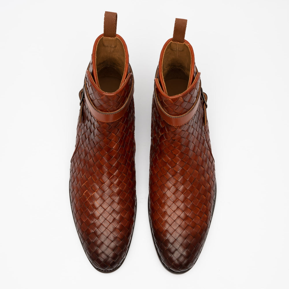 Overhead view of a pair of brown woven leather ankle boots with buckles on a white background.