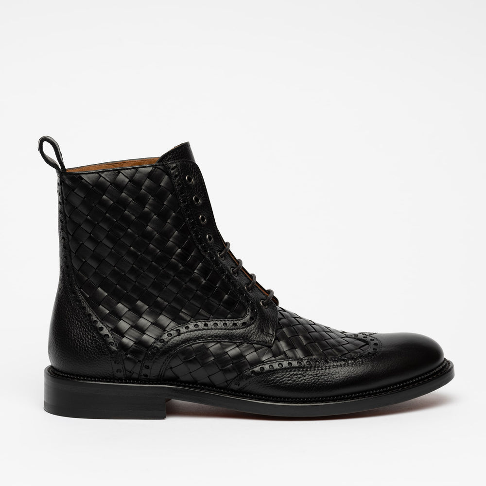 A black leather boot with a woven pattern and brogue detailing, featuring lace-up closure and a pull tab at the heel.