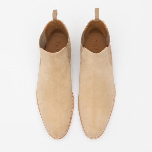 Top view of a pair of khaki suede ankle boots with brown leather soles, pull tabs at the back, and elastic side panels.
