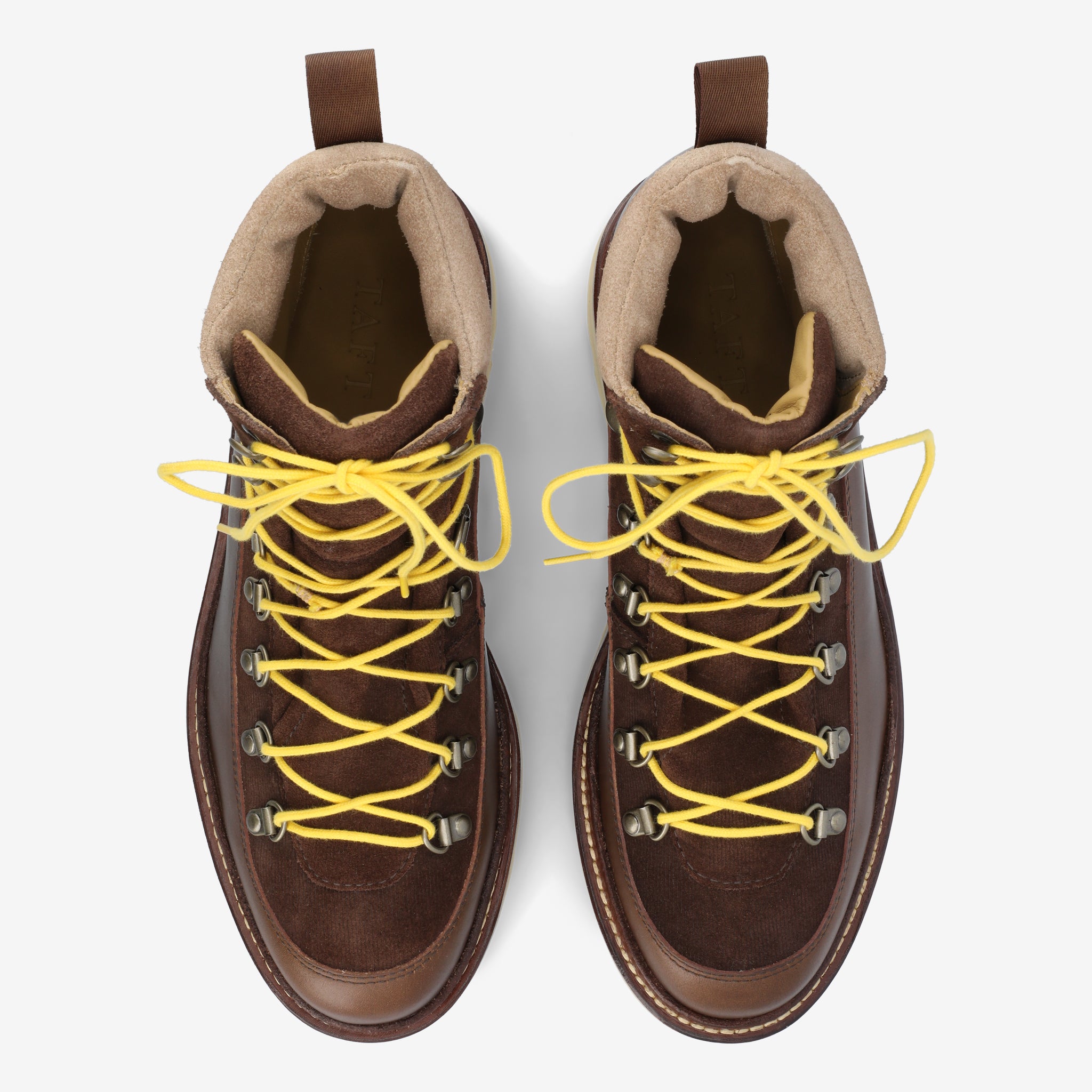 Top view of a pair of brown hiking boots with yellow laces, beige padded linings, and a rugged sole, set against a white background.