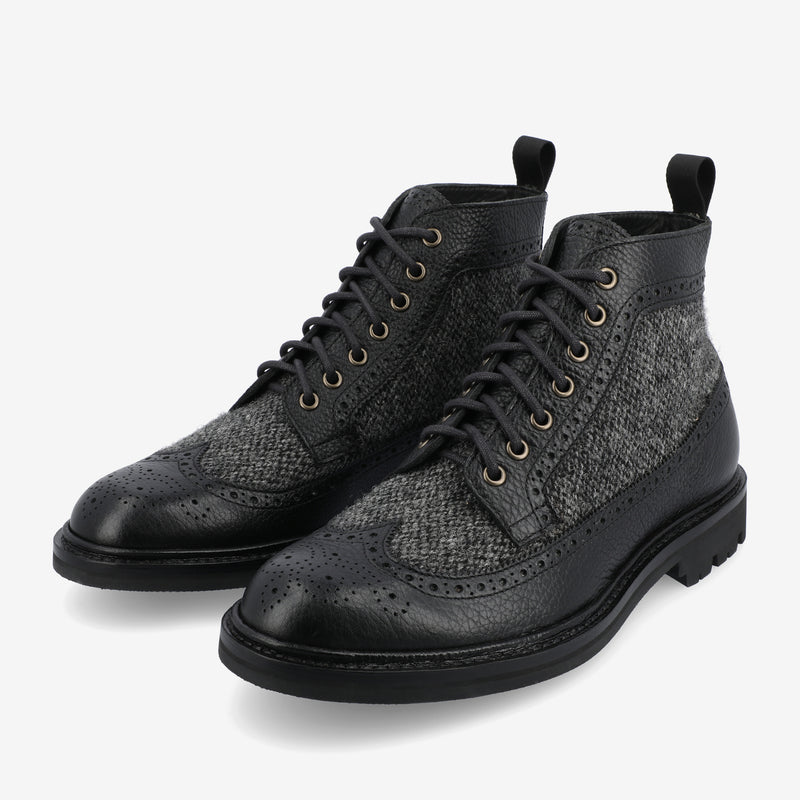 A pair of black leather and grey tweed brogue boots with laces, featuring decorative perforations and pull tabs on the back.