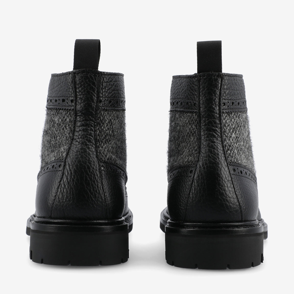 Rear view of a pair of black leather and grey wool blend ankle boots with textured details and pull tabs on a white background.