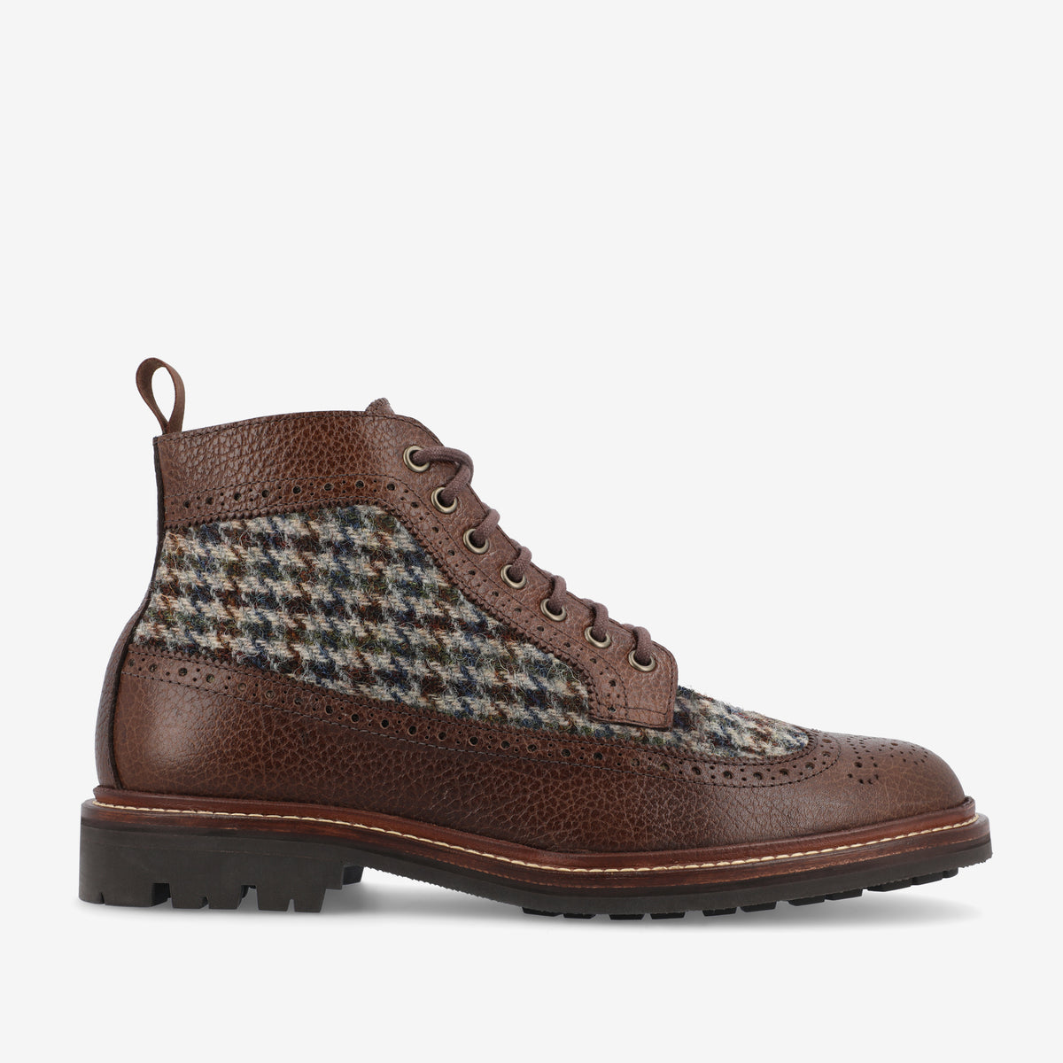 Side view of a brown leather and tweed lace-up boot with a textured rubber sole and ornamental perforations.