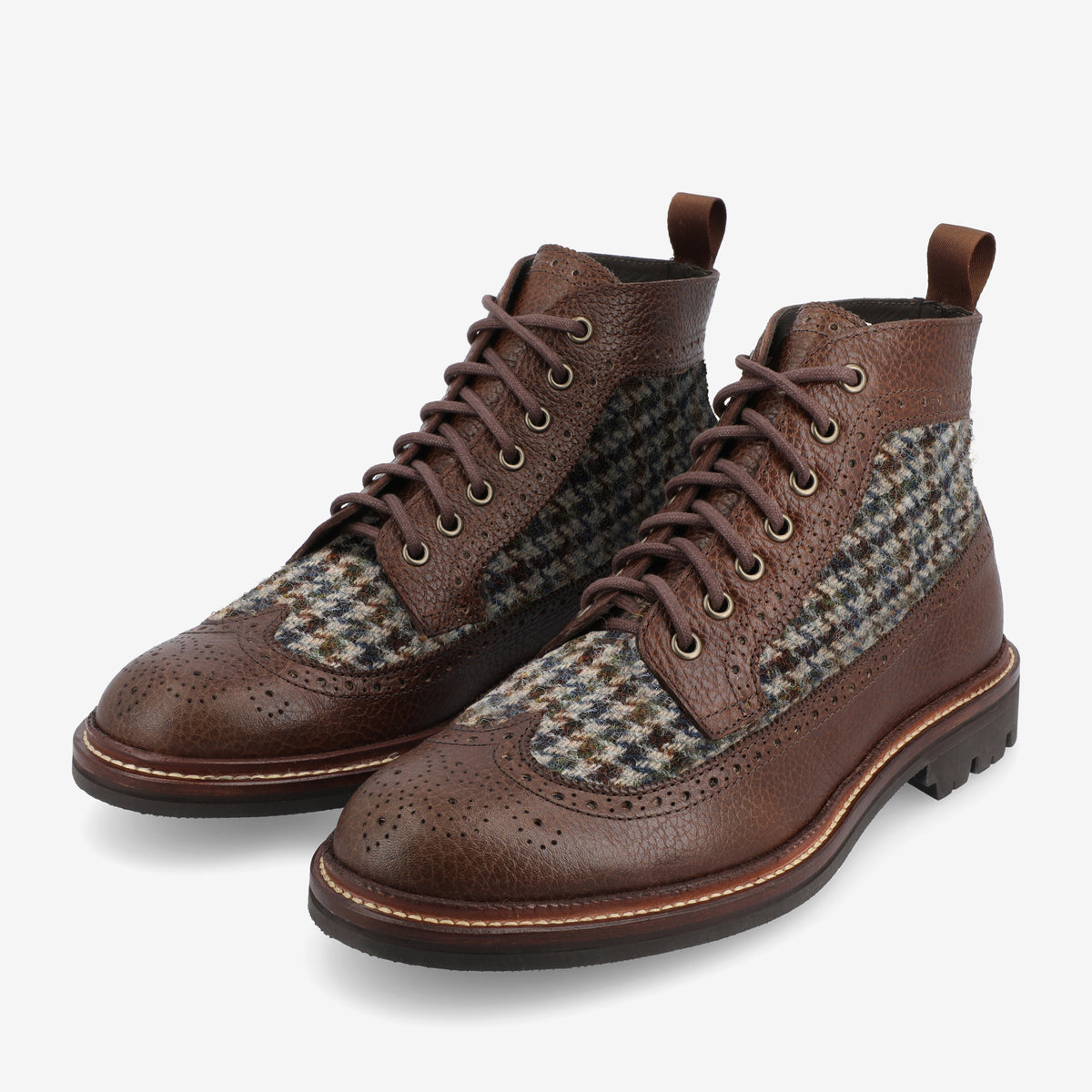 A pair of brown leather and tweed ankle boots with brogue detailing, featuring laces and sturdy soles.