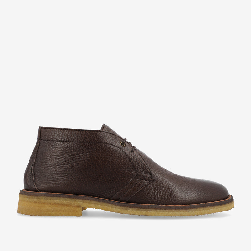 Brown leather chukka boot with lace-up closure and beige rubber sole, displayed on a white background.