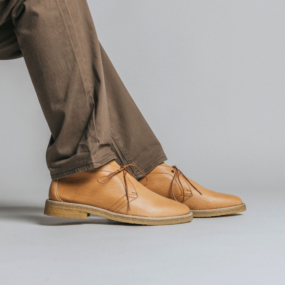 Person wearing light brown leather shoes and brown pants.