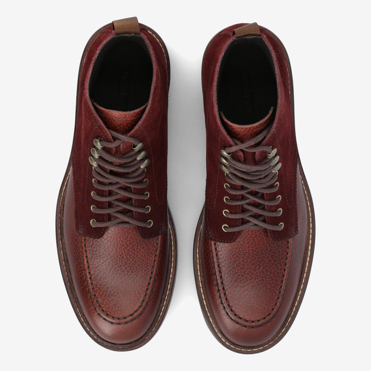 Top view of a pair of brown leather lace-up boots with textured detailing, sitting on a white background.