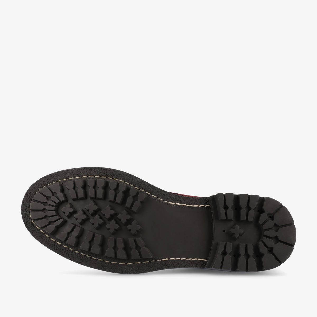 A black rubber sole of a shoe with a lug tread pattern and contrast stitching, viewed from the bottom.