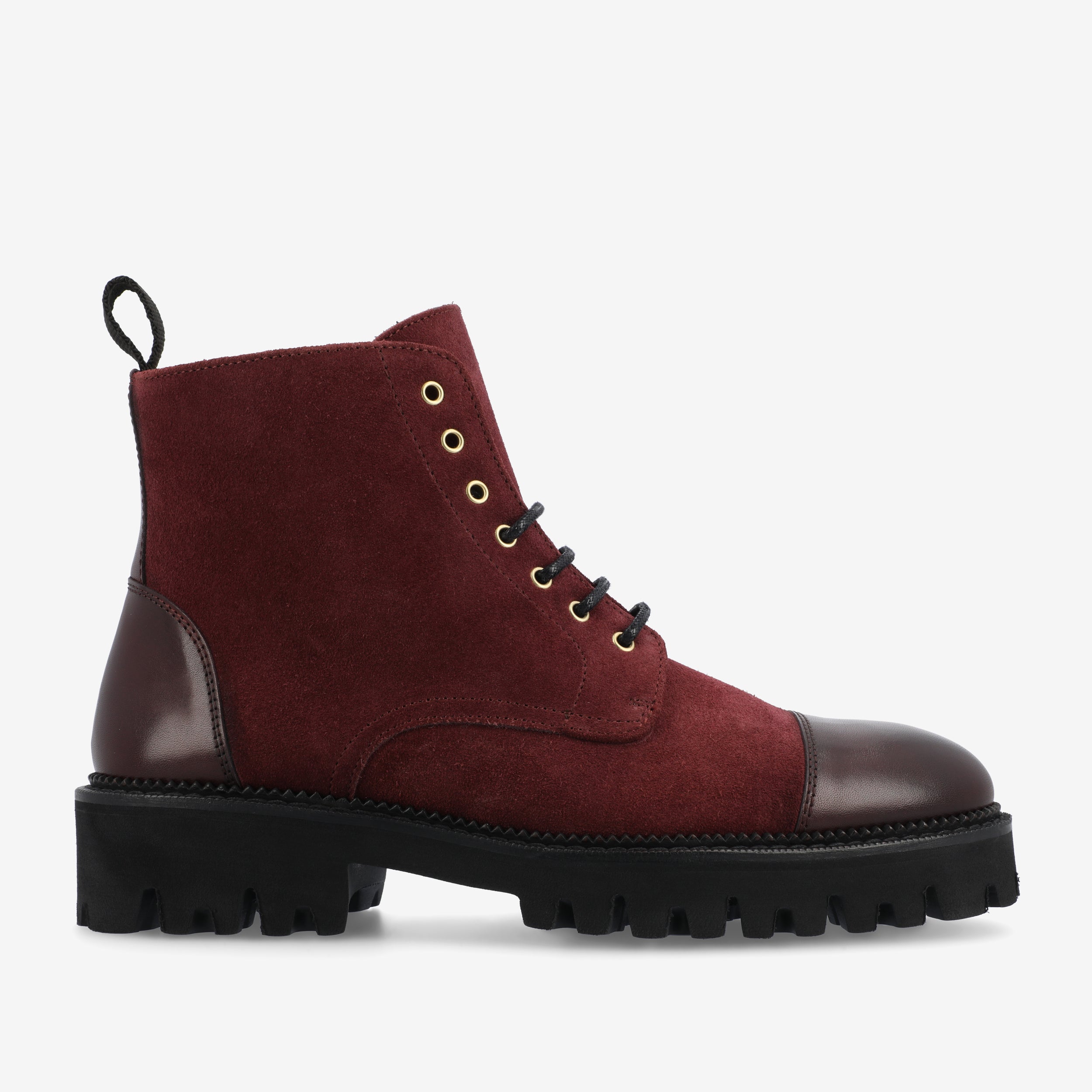 A side view of a maroon suede ankle boot with black laces, a black leather heel cap, gold eyelets, and a black chunky sole.