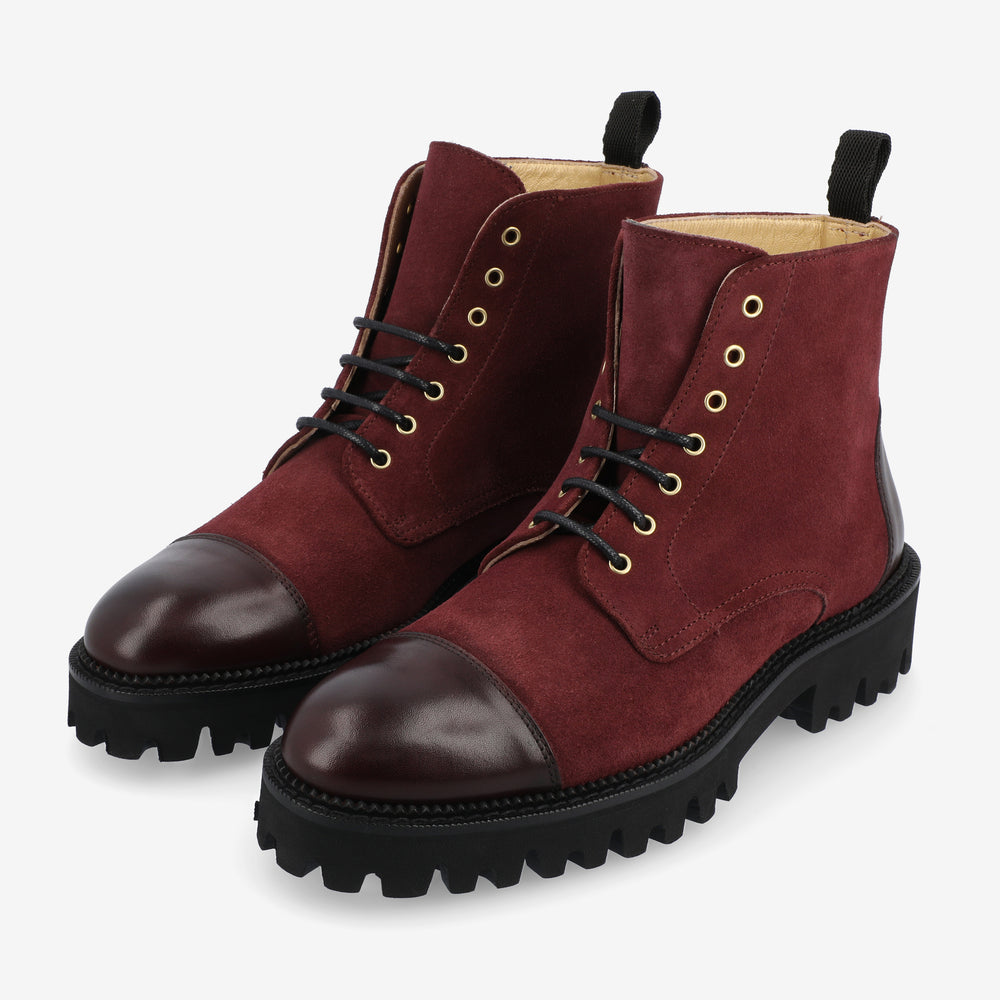 A pair of maroon suede combat boots with black leather toe caps and black laces.