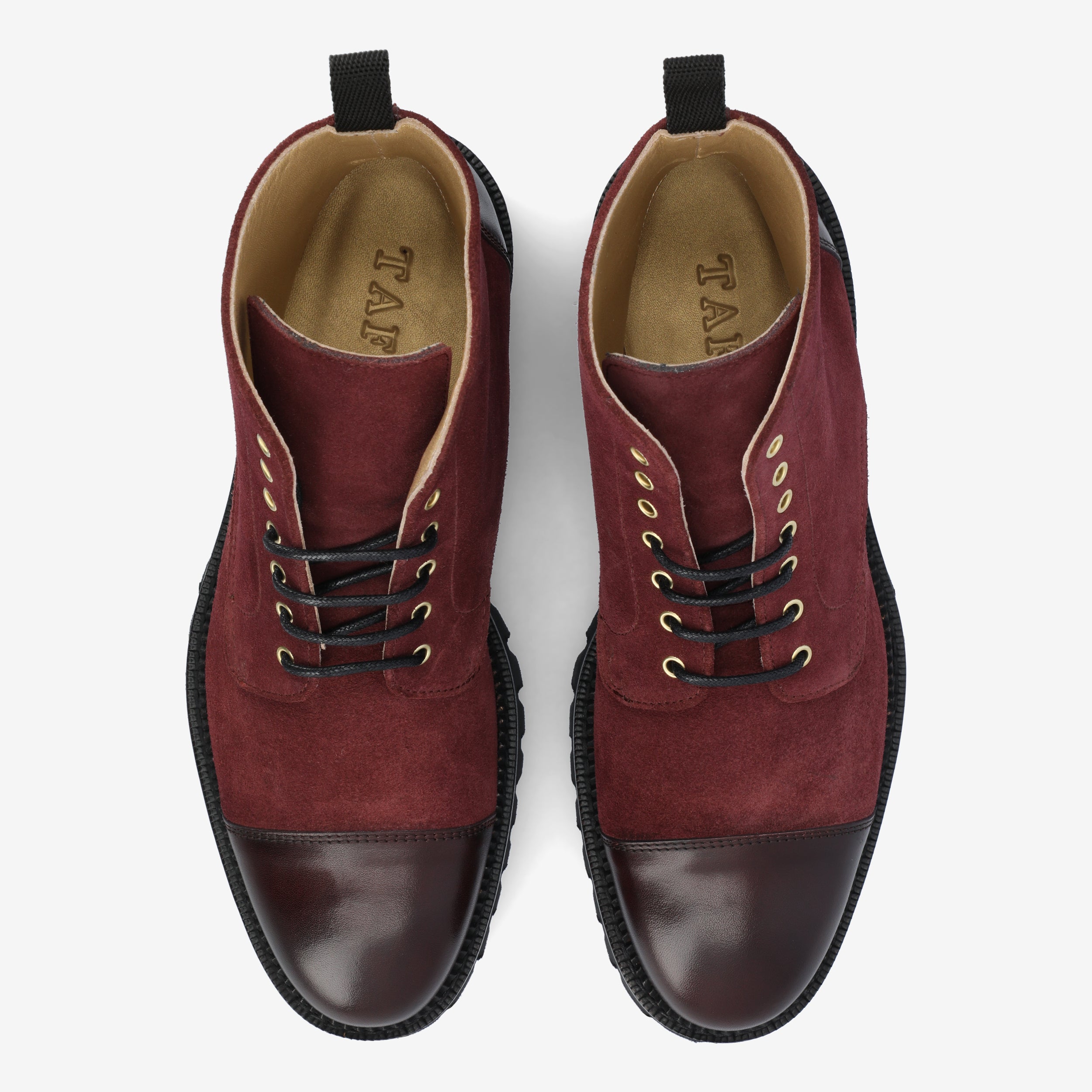 A pair of maroon and dark-brown lace-up boots with black soles, viewed from above.