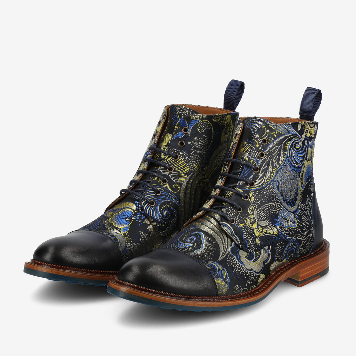 A pair of dark blue ankle boots with intricate floral and paisley patterns in blue, green, and yellow. The boots have black capped toes, wooden soles, and blue pull tabs at the back.