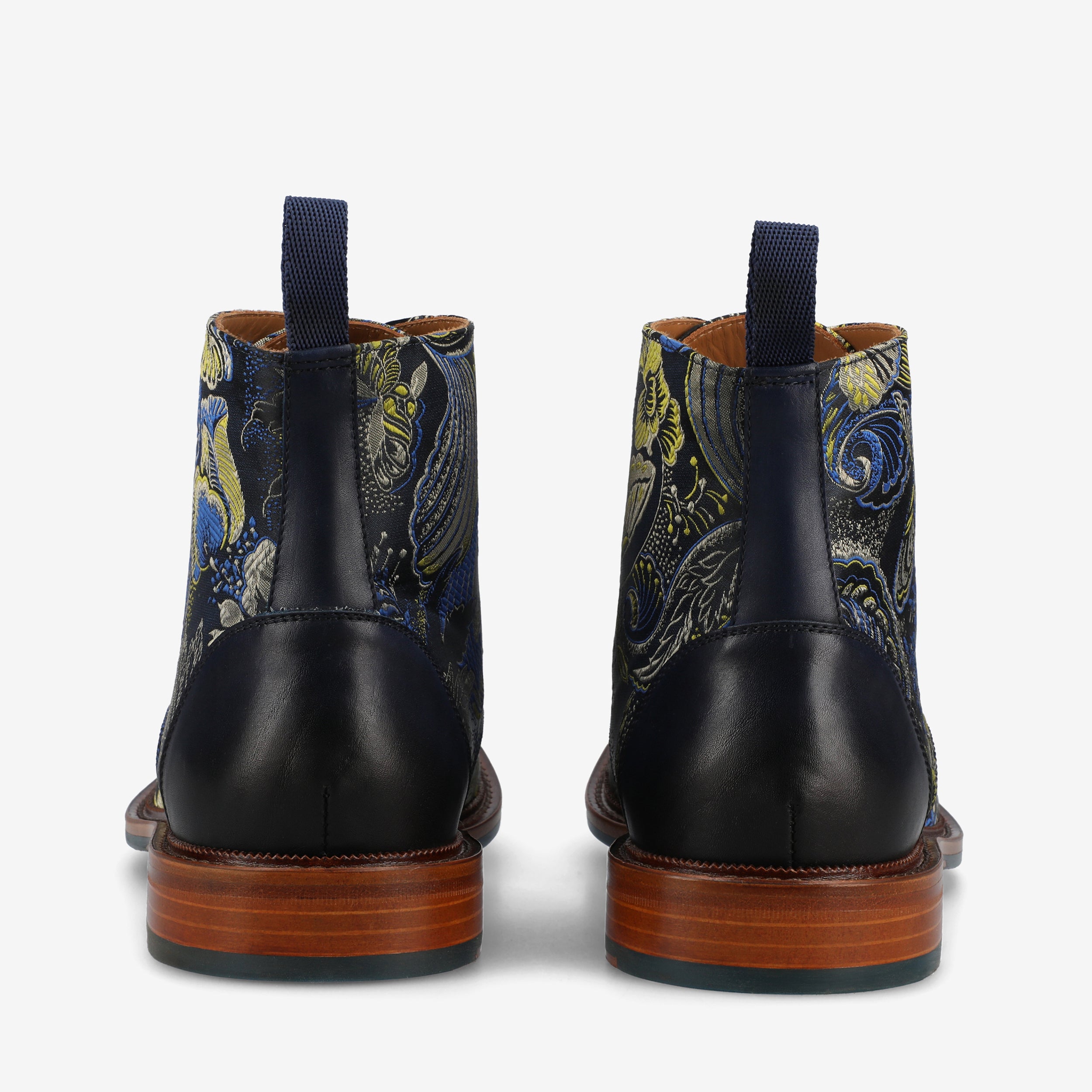 A pair of floral patterned ankle boots with dark blue backs, wooden soles, and heel pull tabs, viewed from the rear.