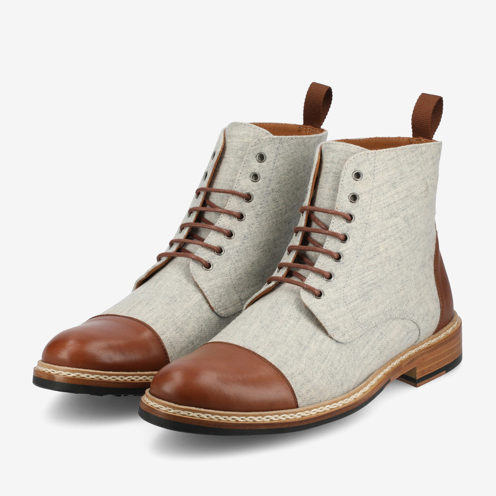 A pair of stylish men's lace-up ankle boots with light grey fabric uppers, brown leather cap toe and heel, brown laces, wooden soles, and brown pull tabs at the back.