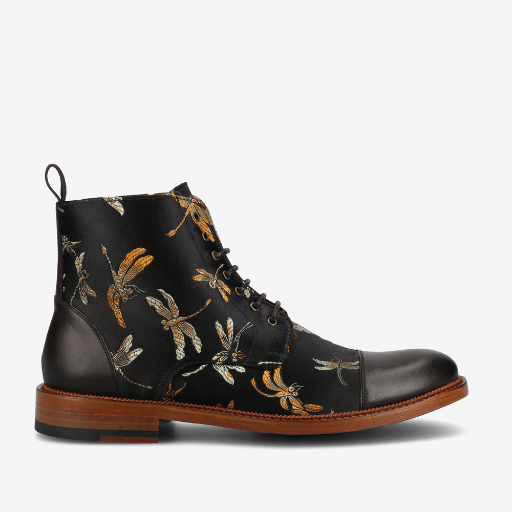 Black leather ankle boot with lace-up front, brown sole, and intricate dragonfly embroidery on the sides.