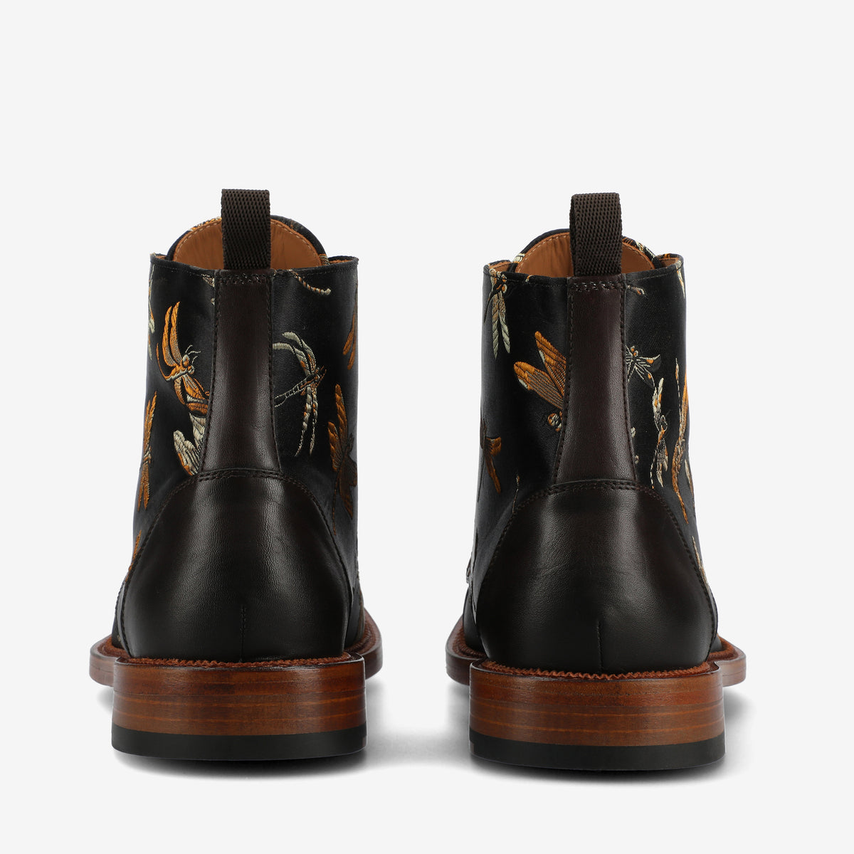 Rear view of two dark leather ankle boots with insect embroidery, wooden soles, and pull tabs.