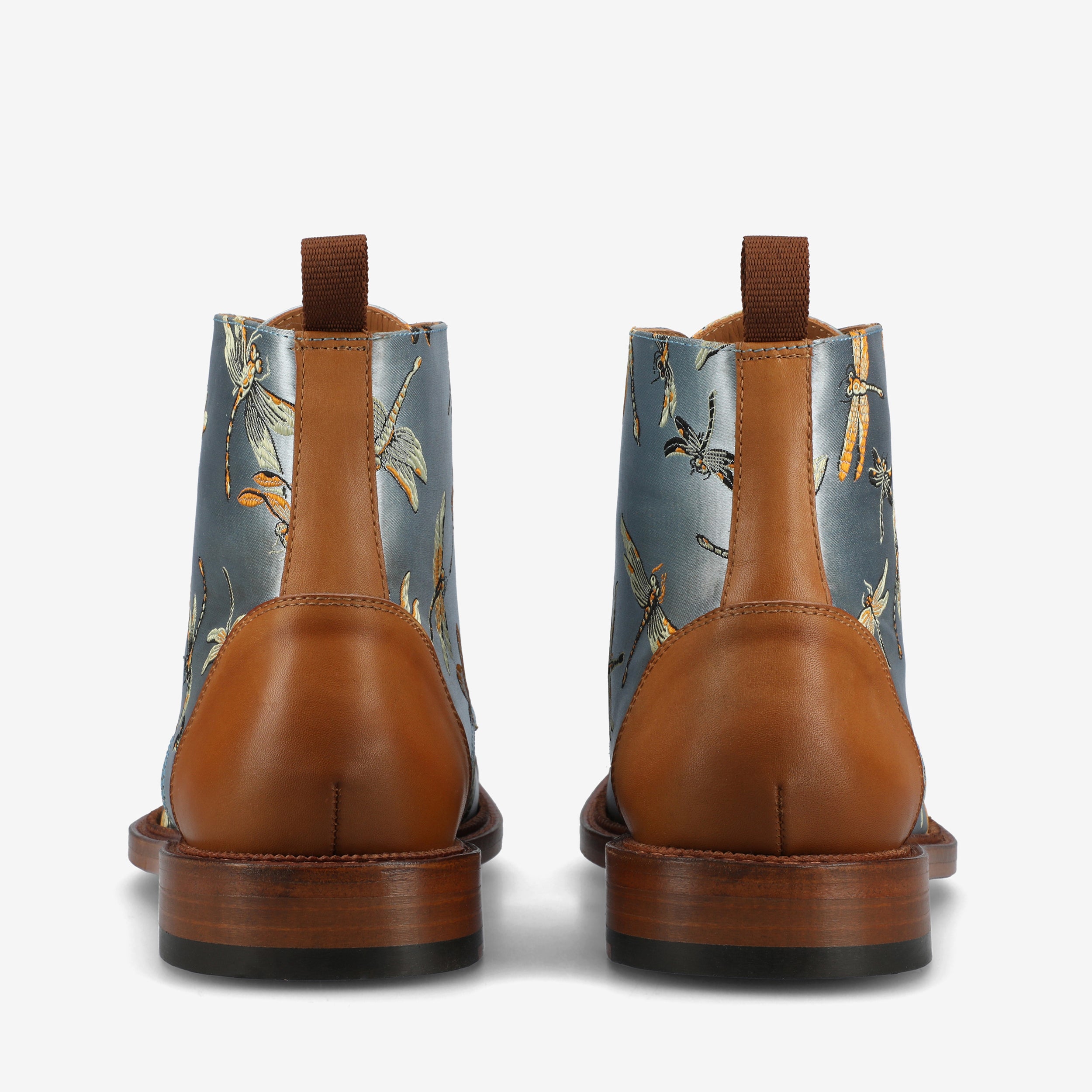 Rear view of brown leather boots with blue fabric inserts featuring a dragonfly pattern, shown against a white background.