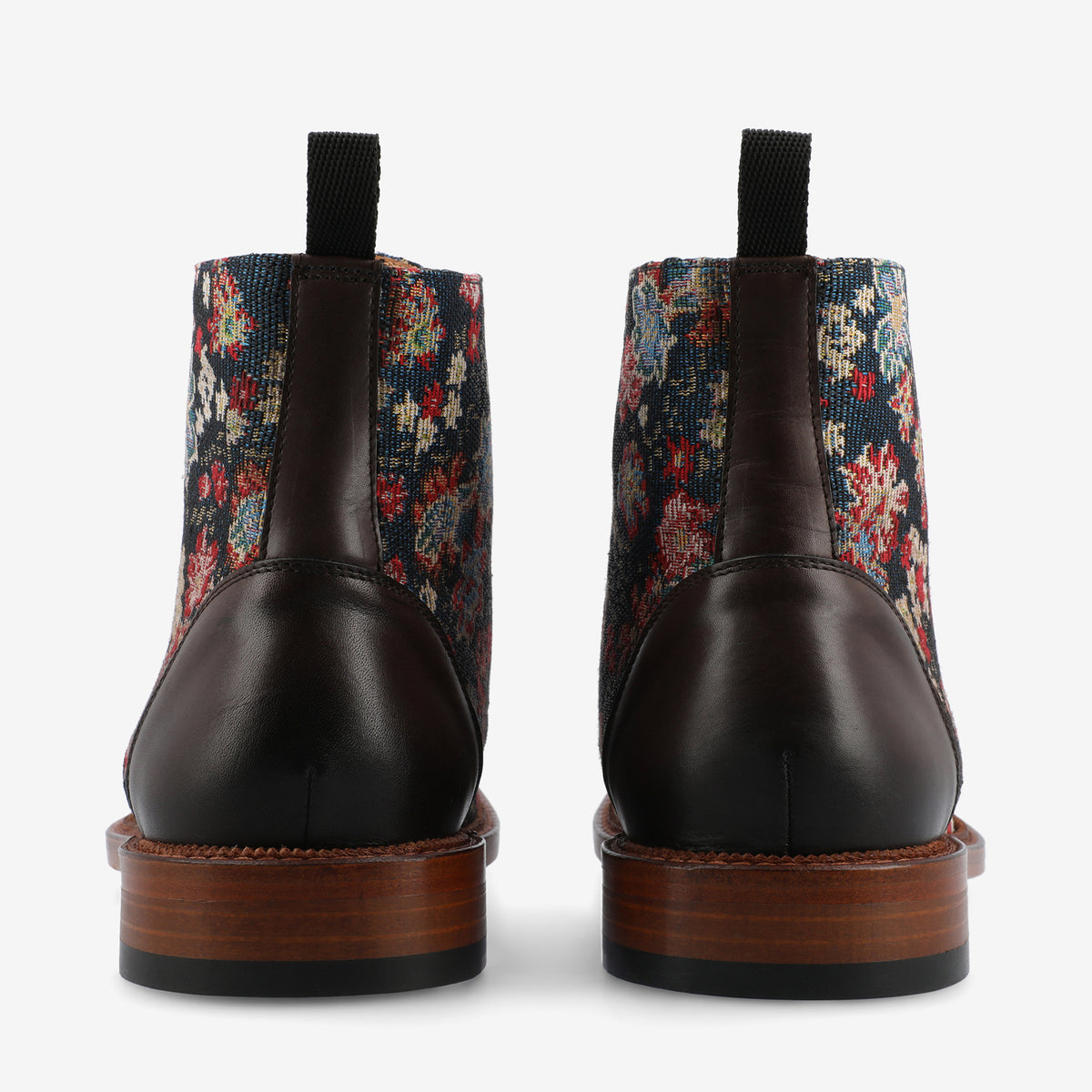 A pair of boots with dark brown leather and a floral-patterned fabric on the back.