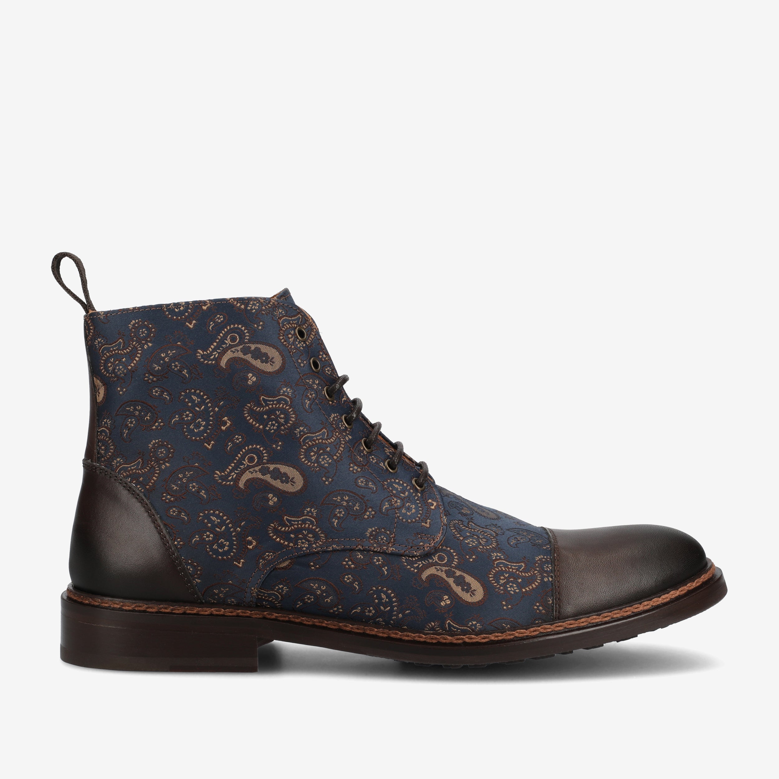 A dark brown leather and navy blue paisley-printed lace-up boot with a brown sole and a pull tab at the back.