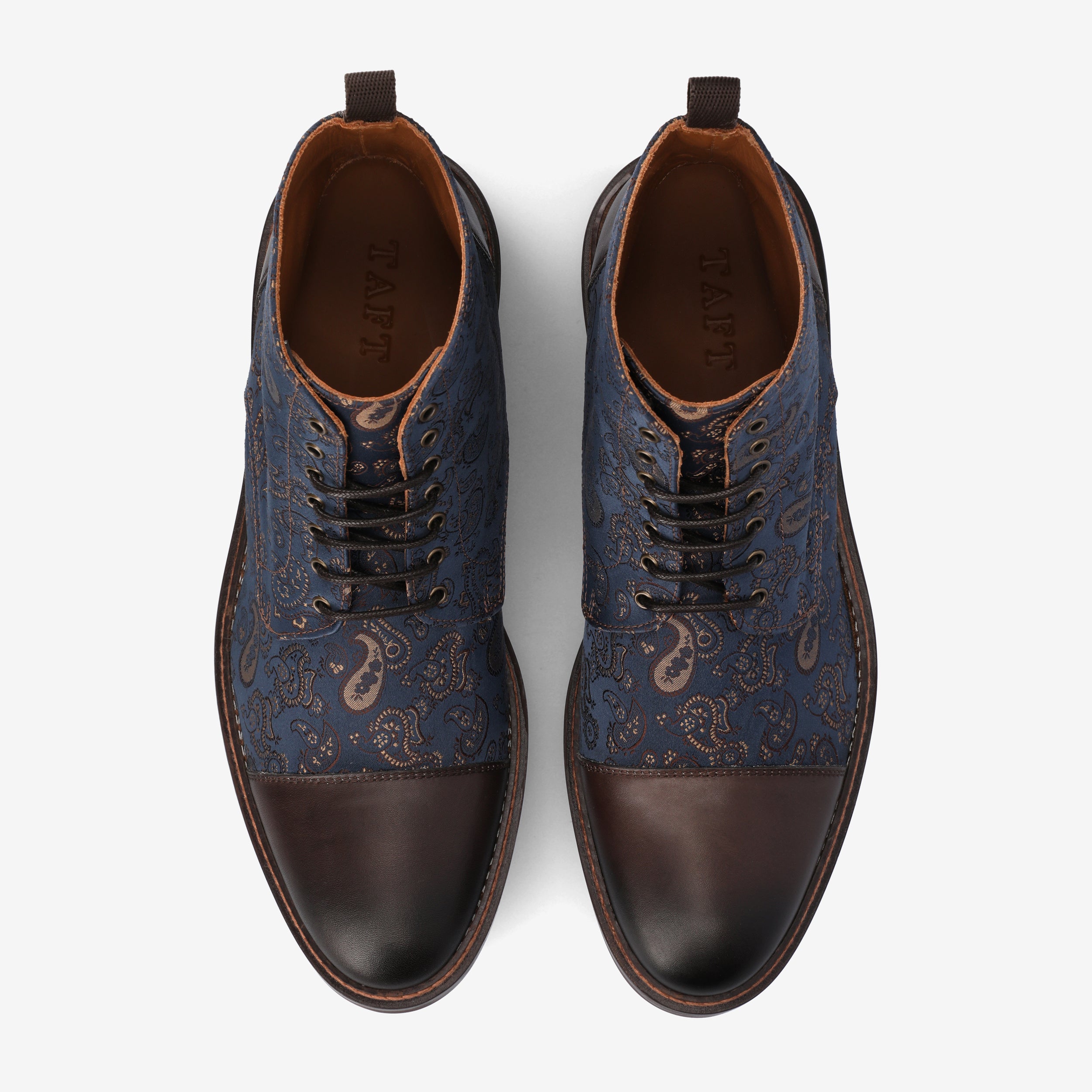 A pair of men's lace-up shoes features a blue and brown paisley-patterned upper with solid brown leather toe caps and brown soles, viewed from above.