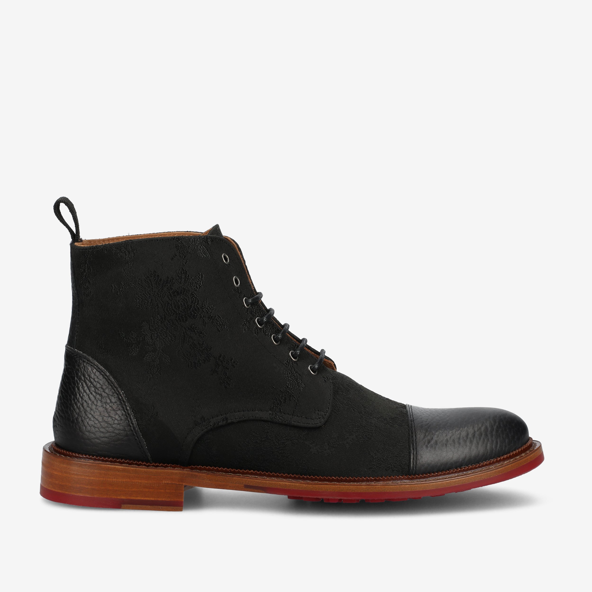 A black leather lace-up boot with a textured upper, black laces, a loop on the back, and a brown and red sole.