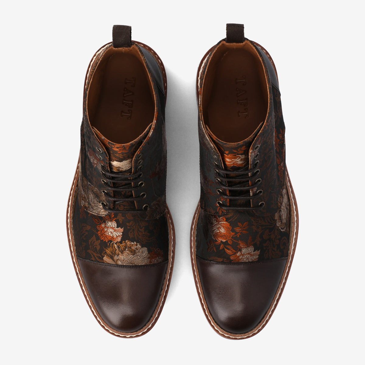 Top view of a pair of dark brown leather boots with floral patterned fabric inserts and TAFT branding inside.