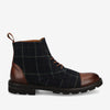 Side view of a dark plaid ankle boot with brown leather toe and heel accents, featuring a black sole and brown laces.