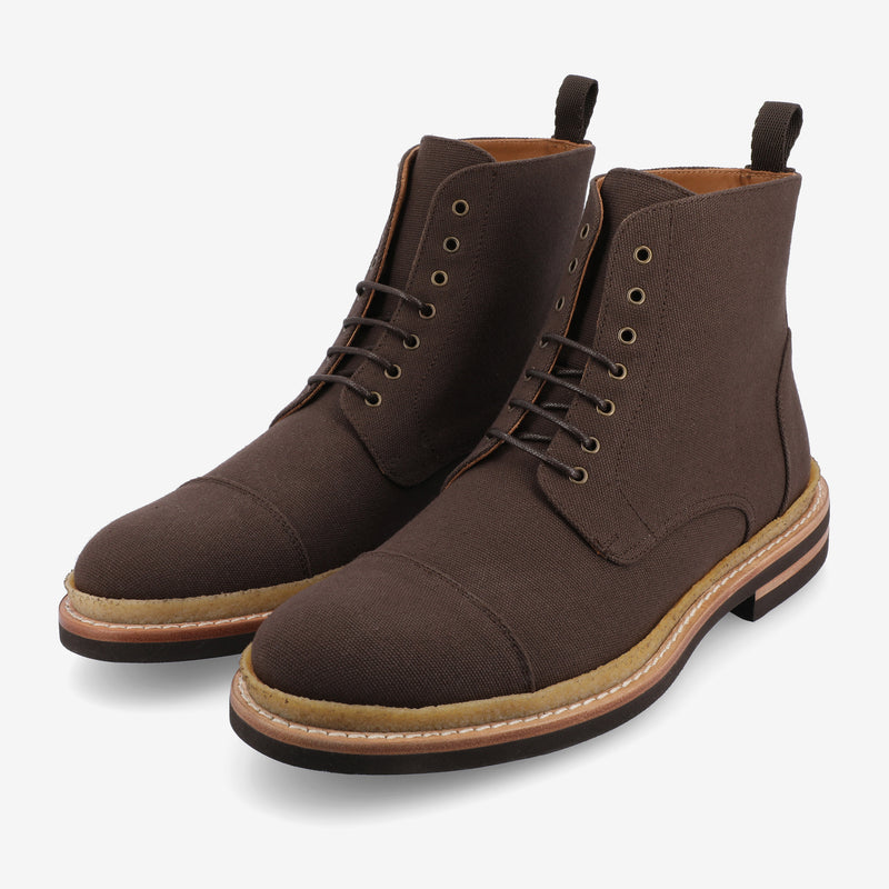 A pair of brown lace-up boots with a cap toe design, featuring a light brown sole and dark brown outsole.