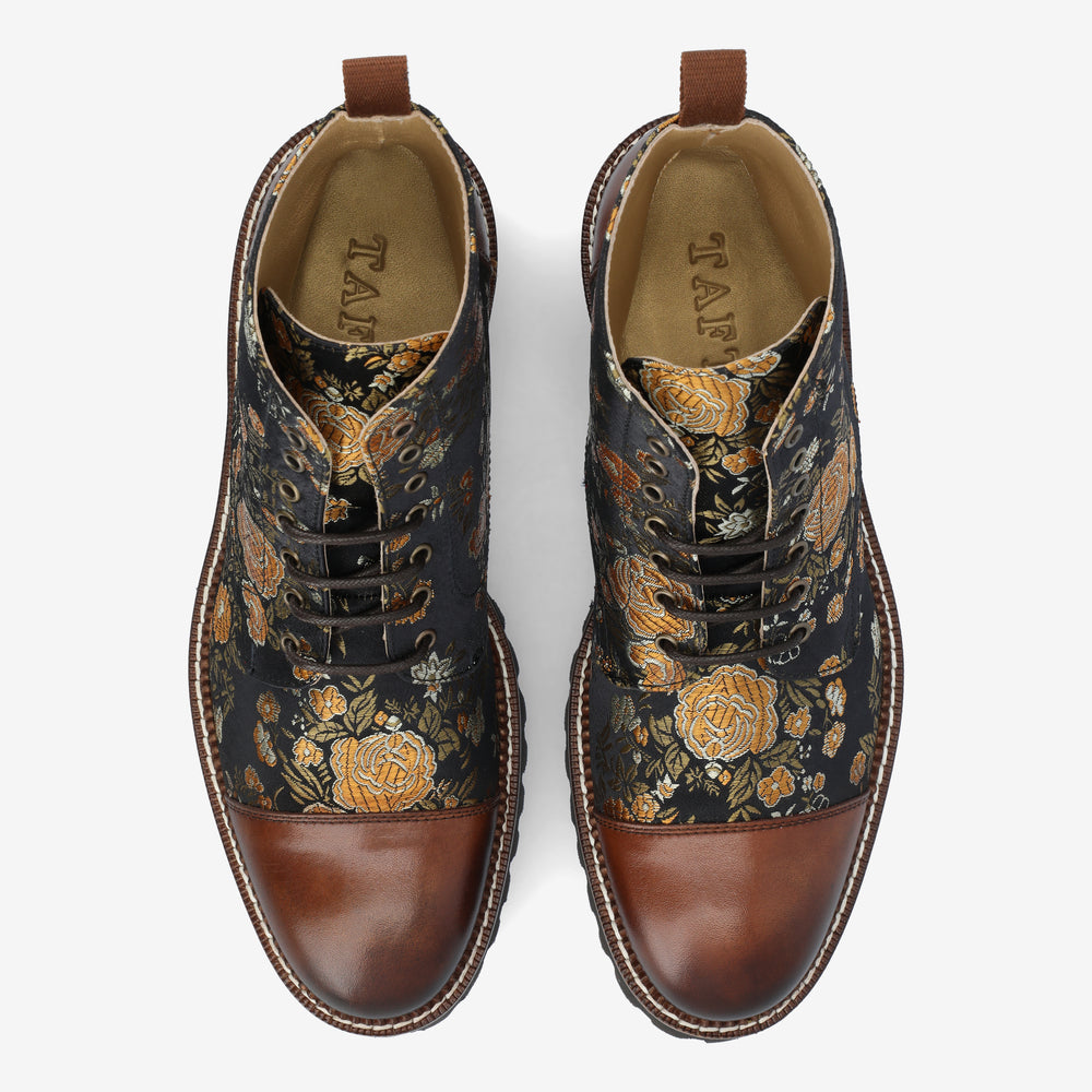 Pair of floral-patterned leather boots with brown toe caps and five black lace holes on each shoe, viewed from above.