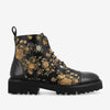 A black leather ankle boot with a thick tread and orange floral embroidery design.