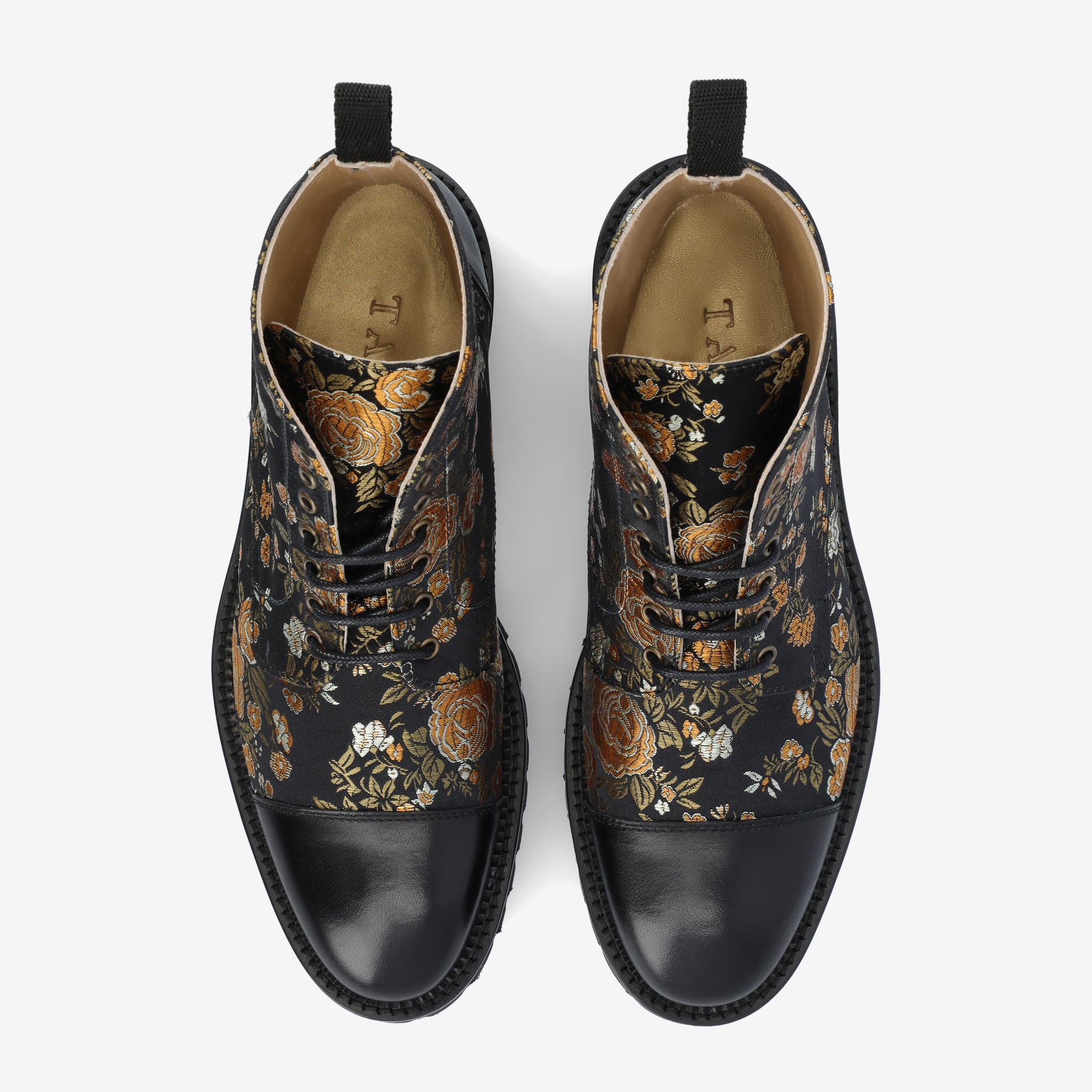 Top view of a pair of black shoes with floral patterns in gold and orange, featuring black leather toe caps and tabs on the heel for easy pull-on.