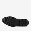 The image shows the bottom view of a black rubber-soled shoe with notable tread patterns for traction.