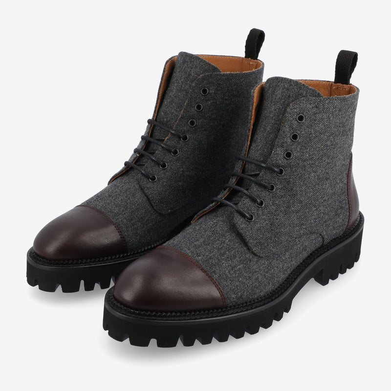 A pair of rugged men's lace-up boots featuring grey wool uppers, dark brown leather toe caps, and thick black rubber soles.