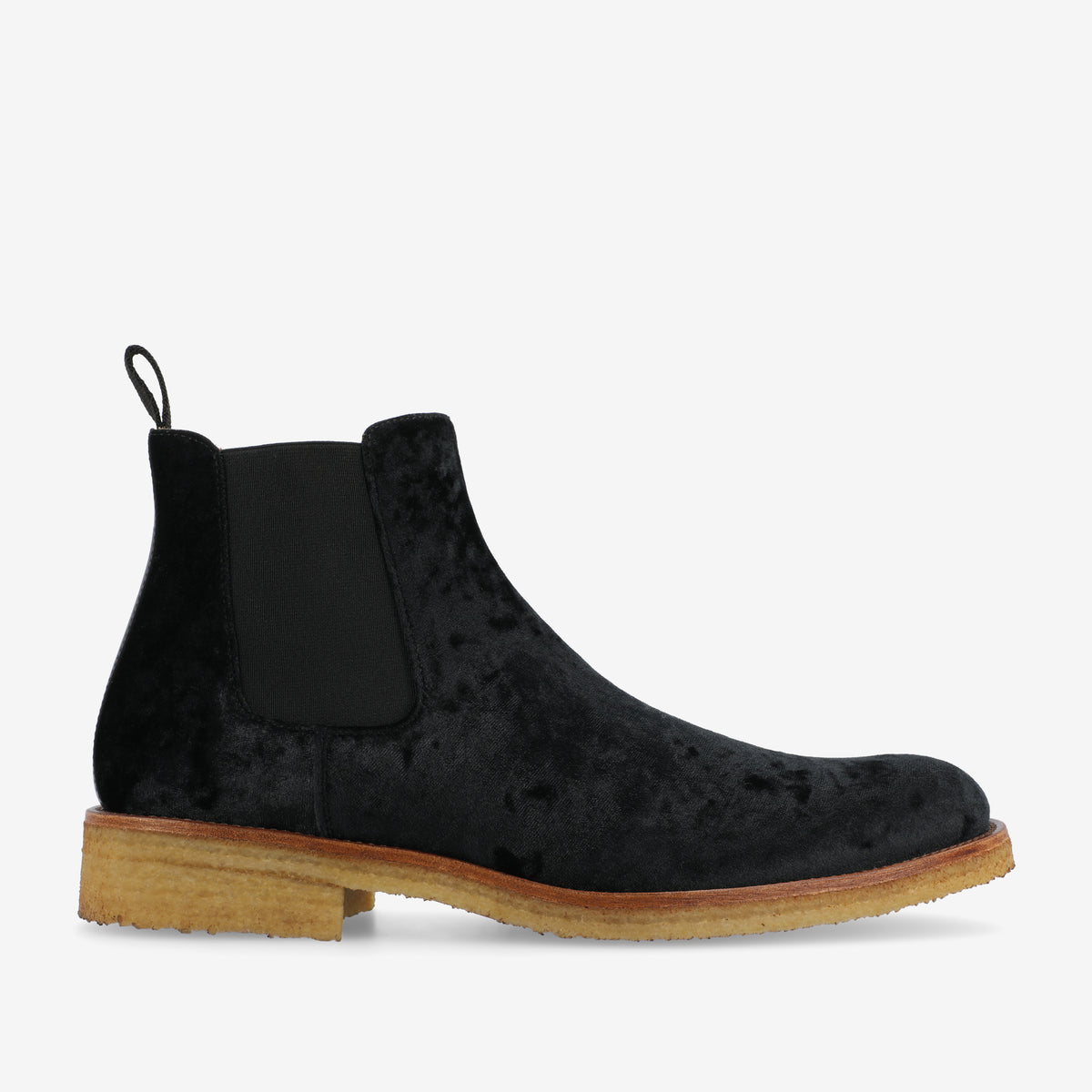 A pair of black velvet Chelsea boots with tan rubber soles and elastic side panels.