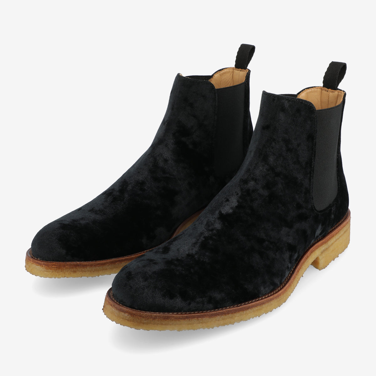 A pair of black velvet Chelsea boots with tan leather soles and elastic side panels, on a white background.