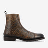 A brown leather boot with intricate floral embossing, featuring a low heel and pull tab at the back.