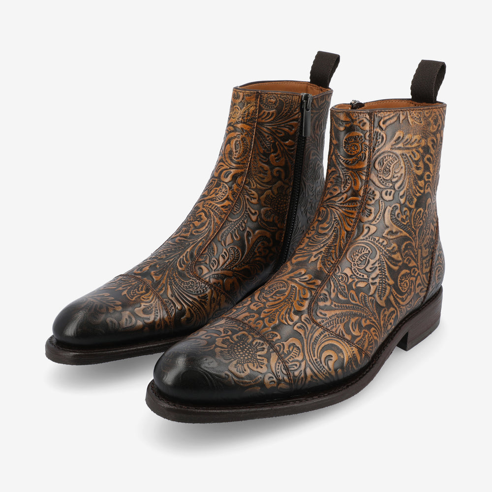 A pair of brown and black leather boots with intricate floral patterns and side zippers.