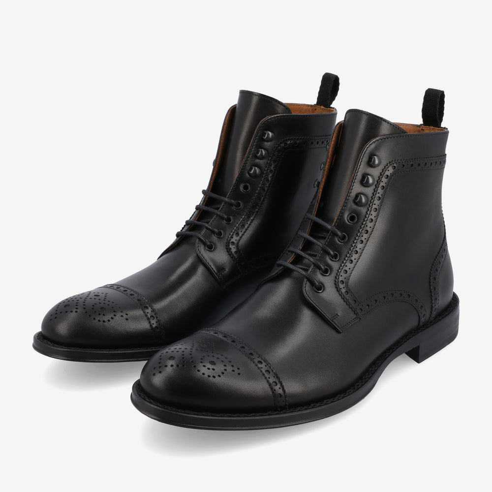 A pair of black leather brogue boots with intricate perforated detailing on the toe caps and sides.