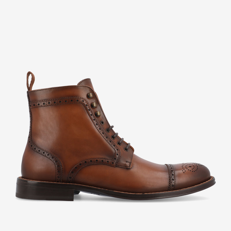 Brown leather brogue ankle boot with decorative perforations, lace-up front, and a pull tab at the back, shown on a white background.