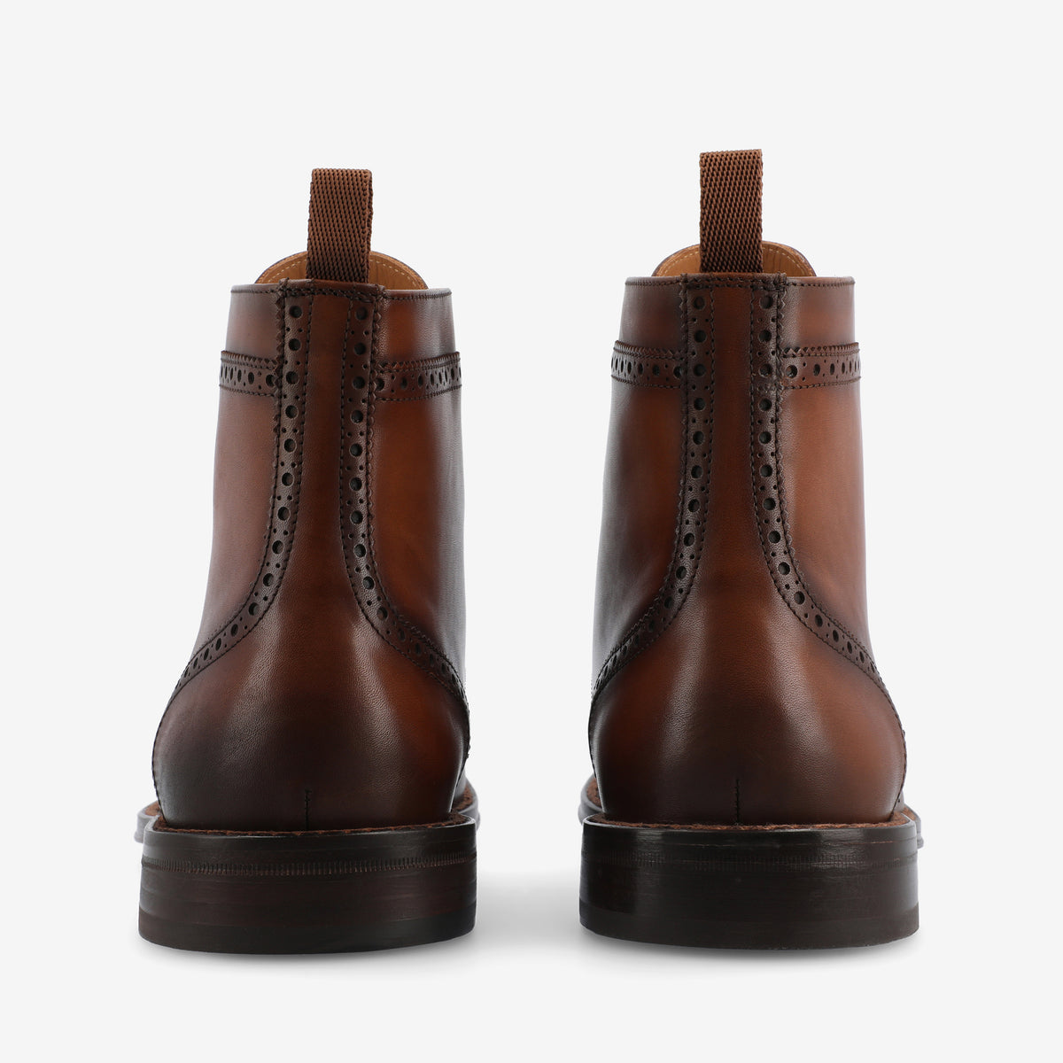 A pair of brown leather boots shown from the back, featuring decorative perforations and pull tabs.