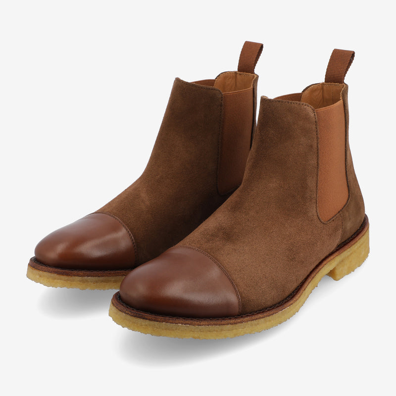 A pair of brown suede and leather Chelsea boots on a white background.