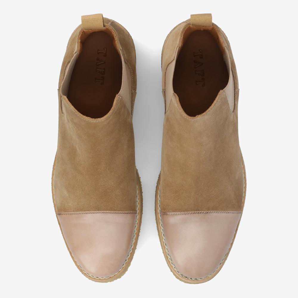 A pair of tan and beige suede slip-on shoes with a rounded metallic cap toe. The brand name TAFT is visible inside each shoe.