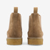 A pair of light brown suede Chelsea boots with beige elastic side panels and rubber soles, viewed from the back.