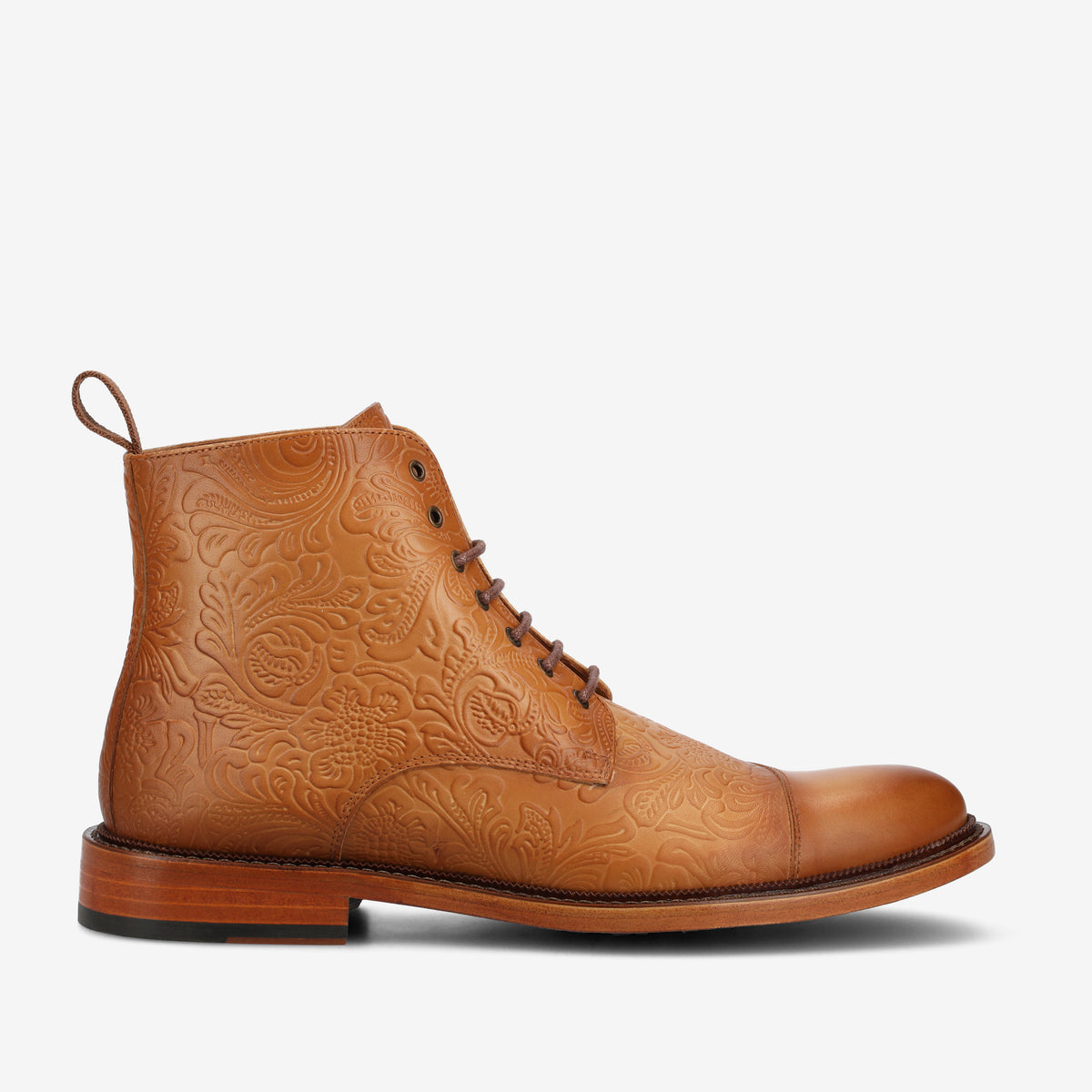 A tan leather lace-up boot with intricate embossed floral patterns, a tab at the back, and a wooden sole.